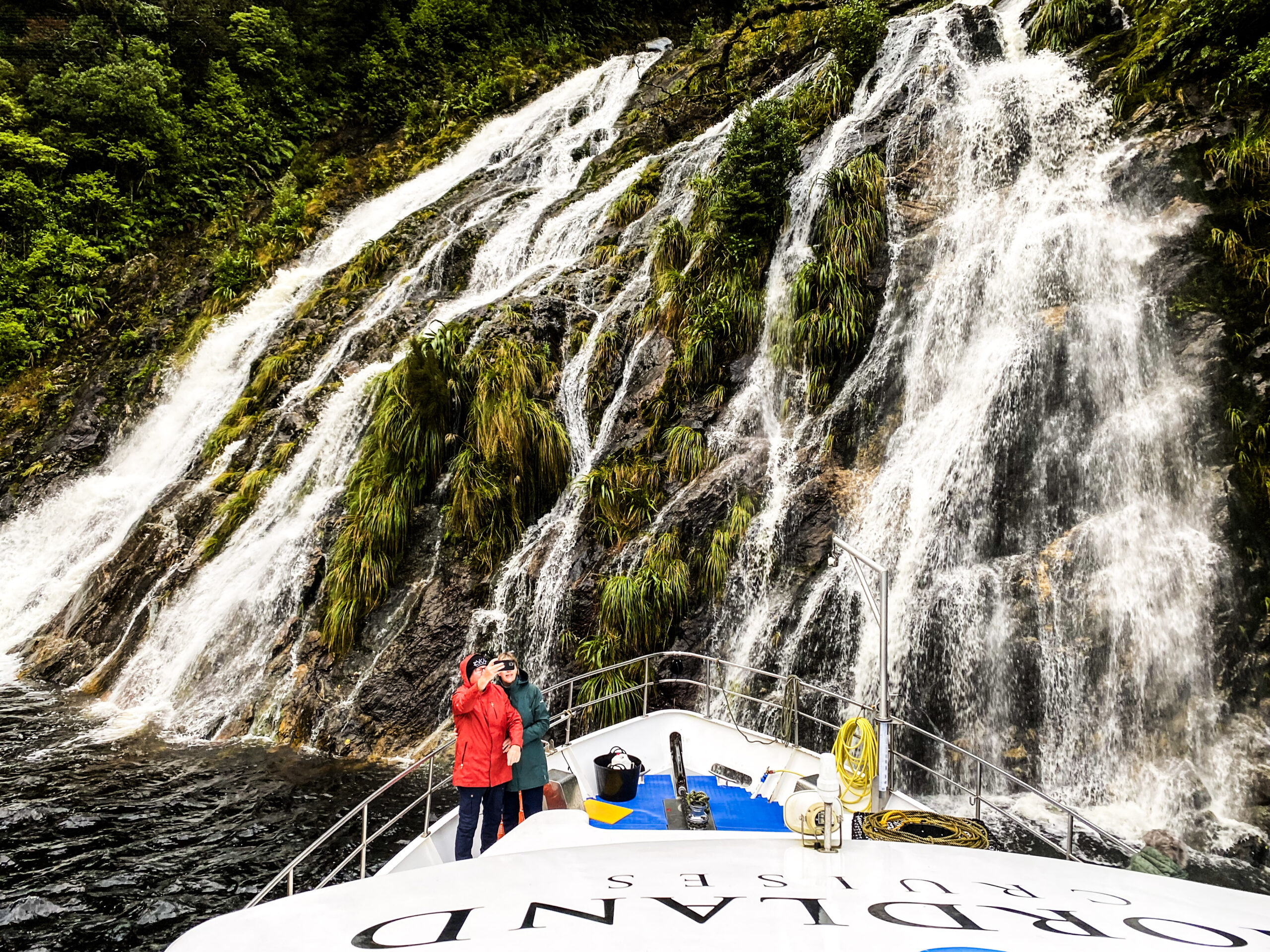 Southern Secret boat poking nose in to waterfall in Fiordland